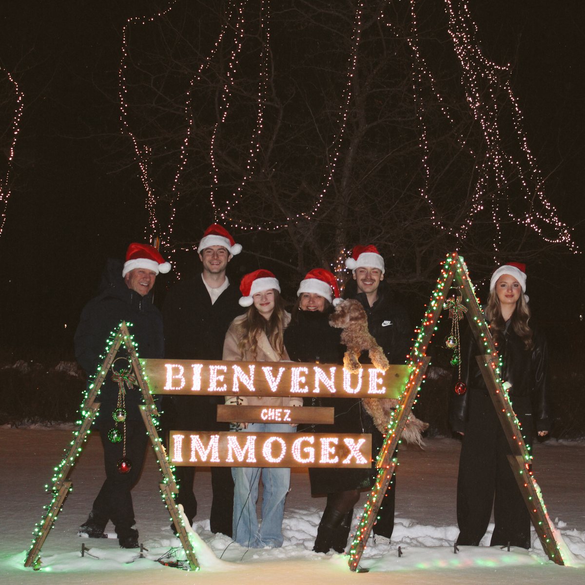 L'équipe réunie pour les fêtes devant l'affiche « Bienvenue chez Immogex »